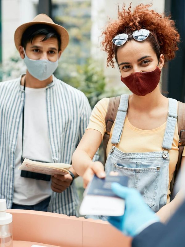 young-traveling-couple-wearing-protective-face-mask-during-check-in-at-hotel-reception-1-1.jpg